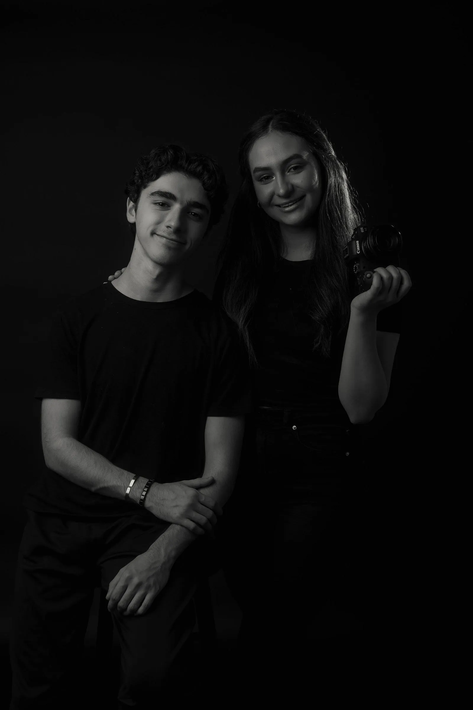 Damaris y Andrés, de Dream Studio, sobre fondo oscuro: él sonríe y ella sostiene una cámara.