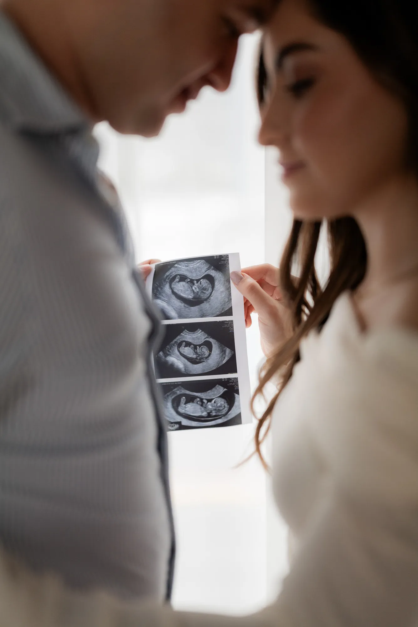 Primer plano de una pareja con un ultrasonido entre ellos.