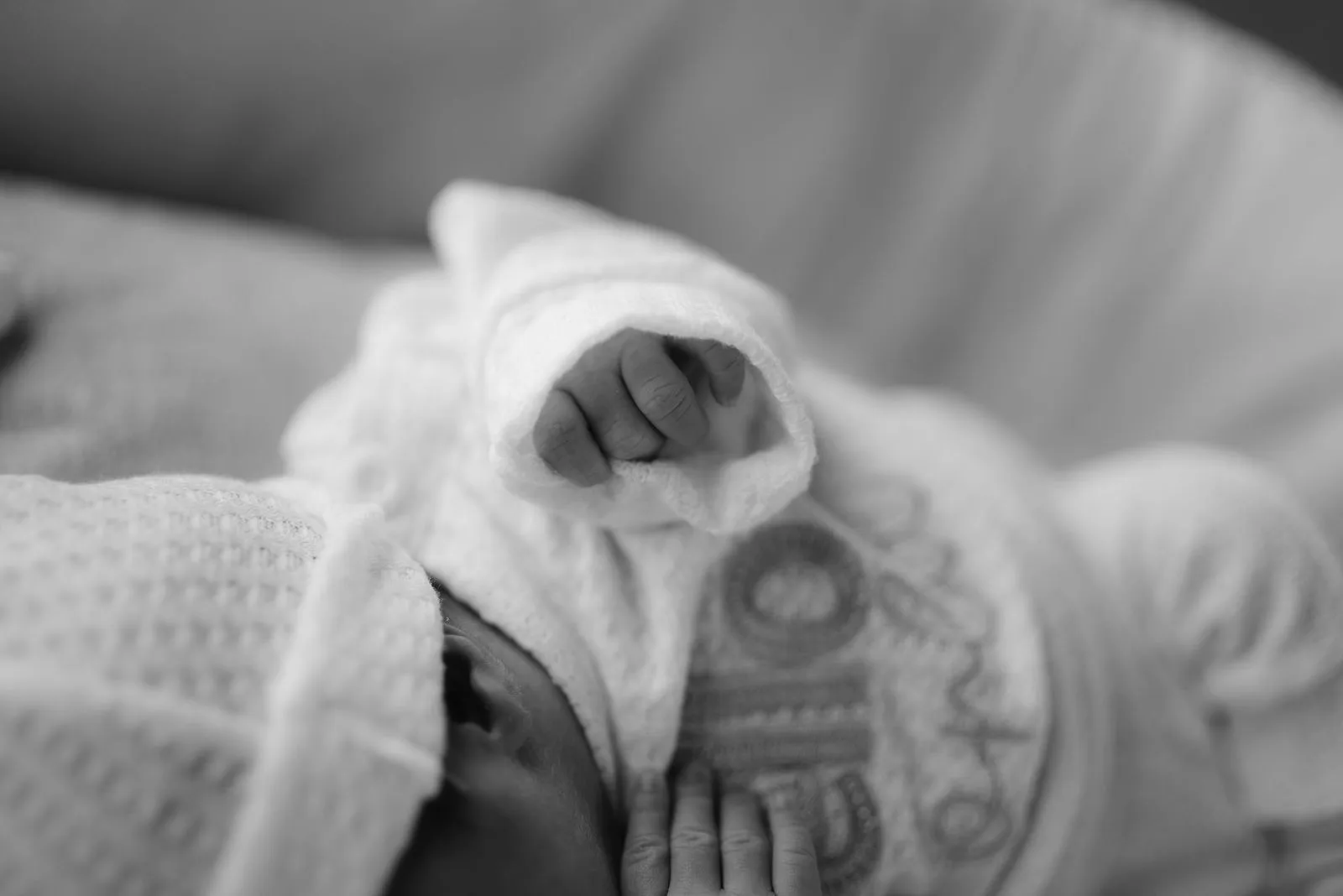 En blanco y negro, detalle de los piecitos de un bebé con gorro tejido.