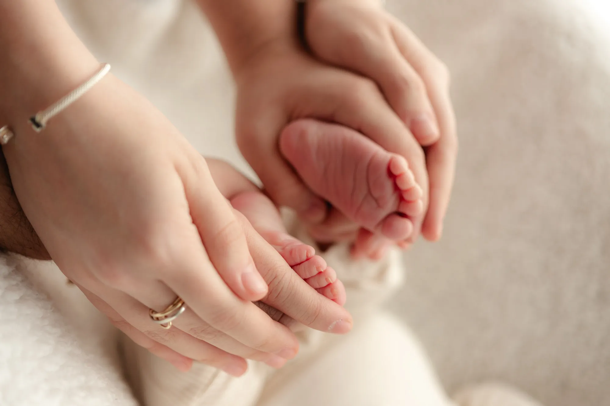 Las manos de unos papás sostienen los pies de su bebé.
