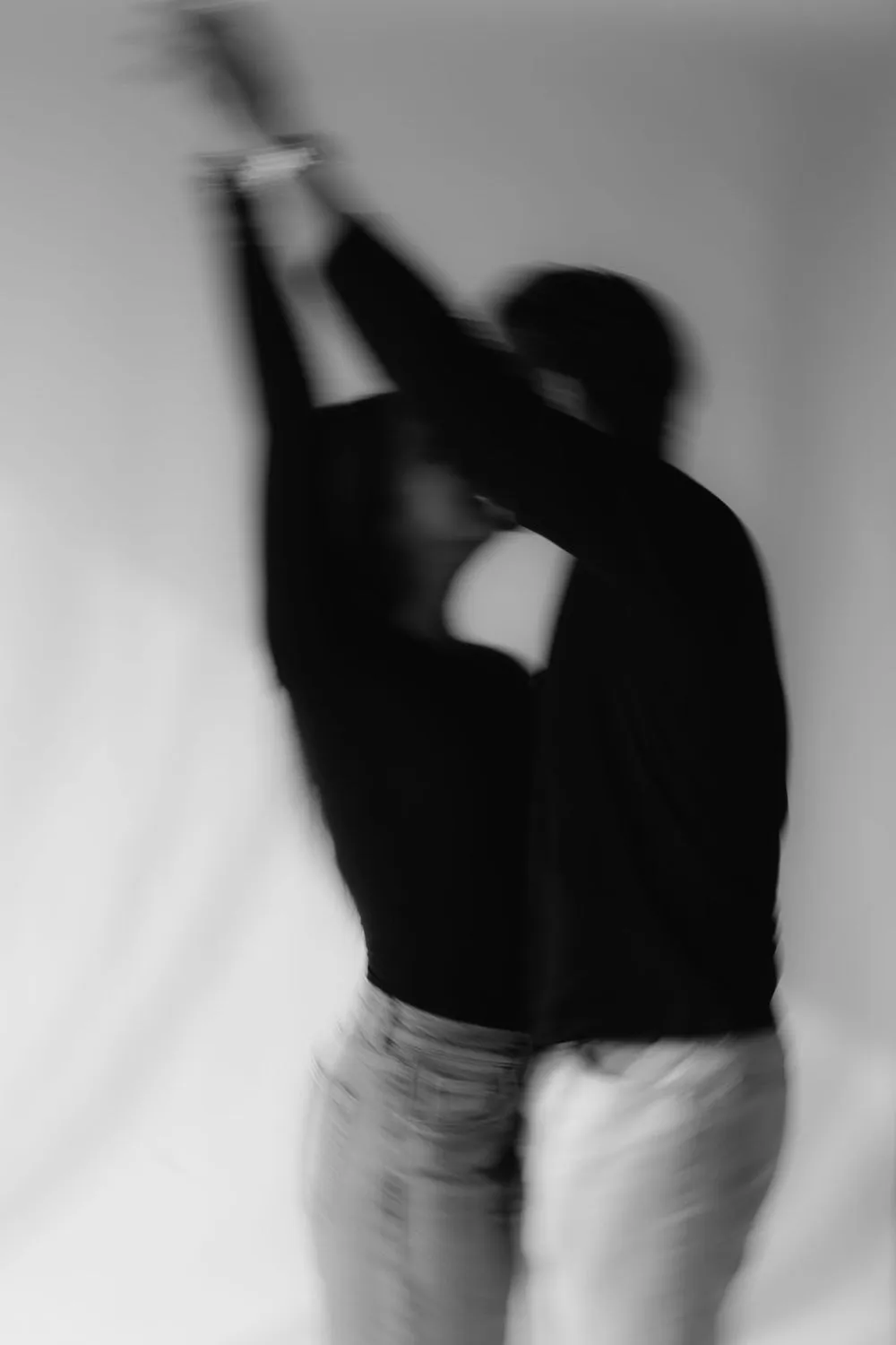 En blanco y negro, una pareja en movimiento, con la imagen desenfocada; ella levanta los brazos.