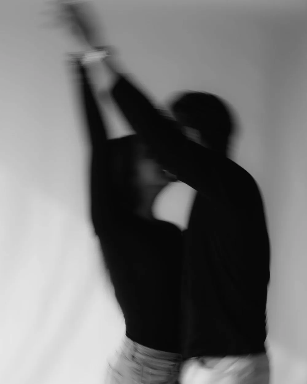 En blanco y negro, una pareja en movimiento, con la imagen desenfocada; ella levanta los brazos.
